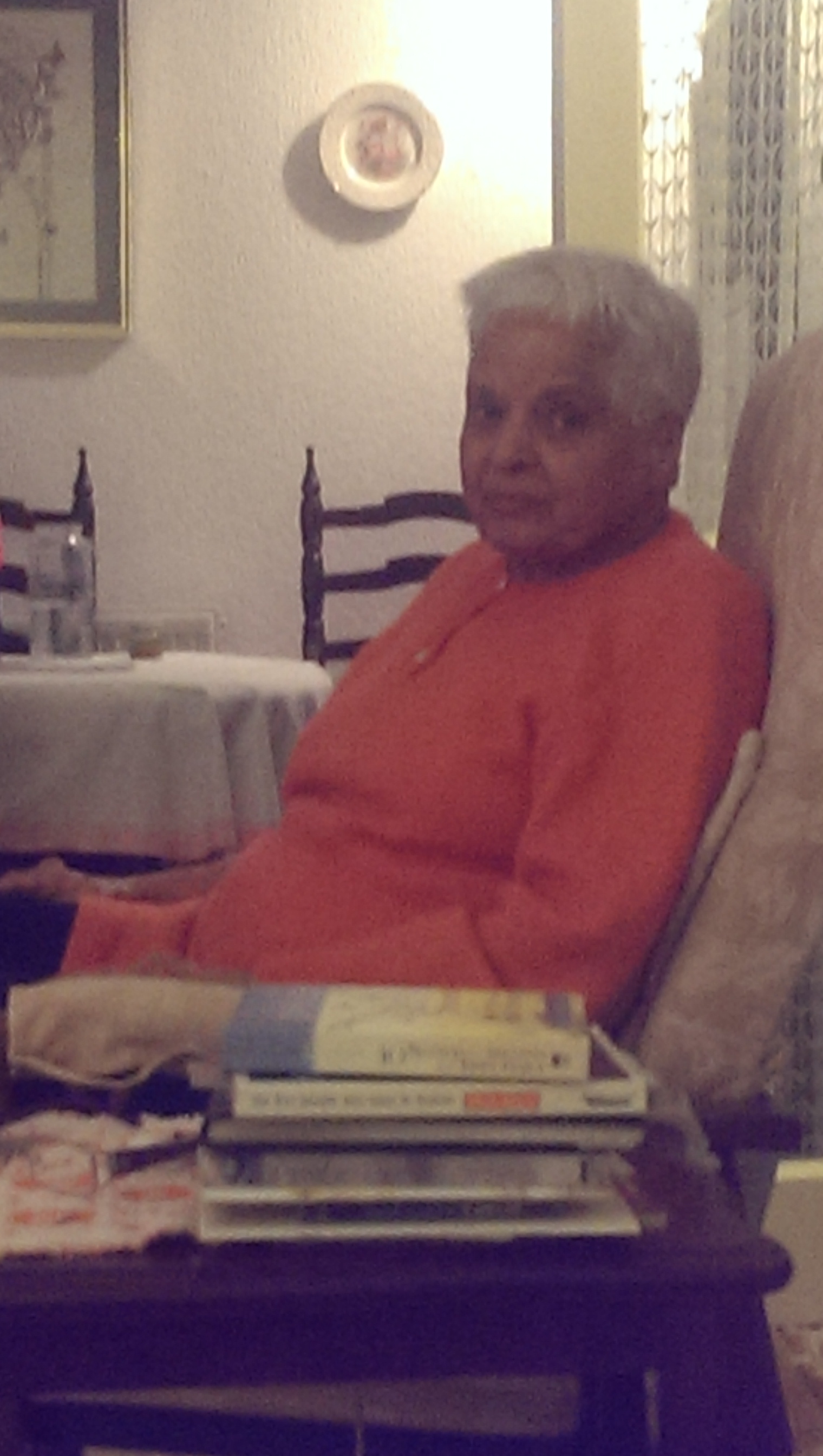 Surjit sitting in her favourite chair in her orange sweater