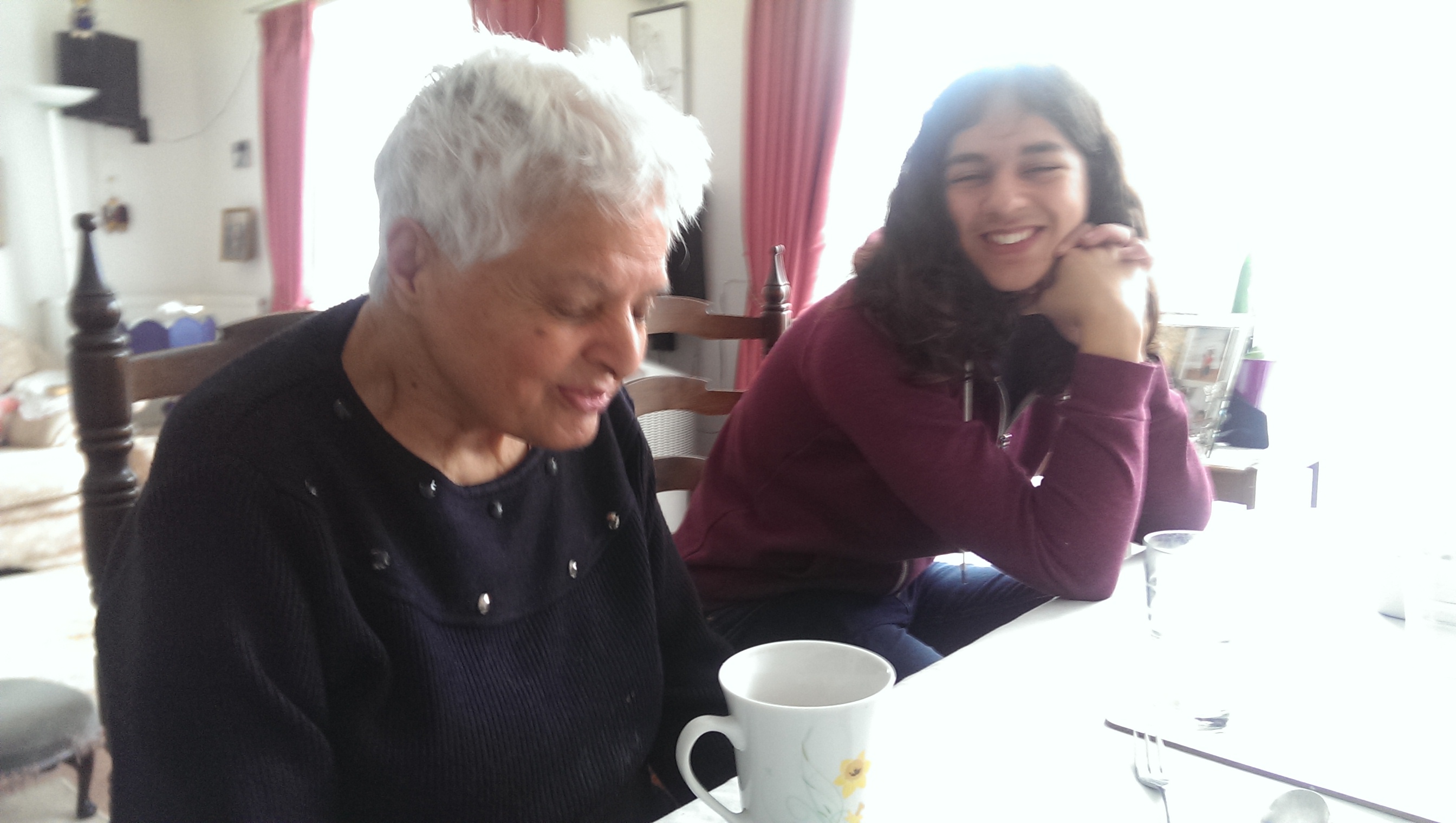 Surjit sharing a laugh at the dining table with a granddaughter