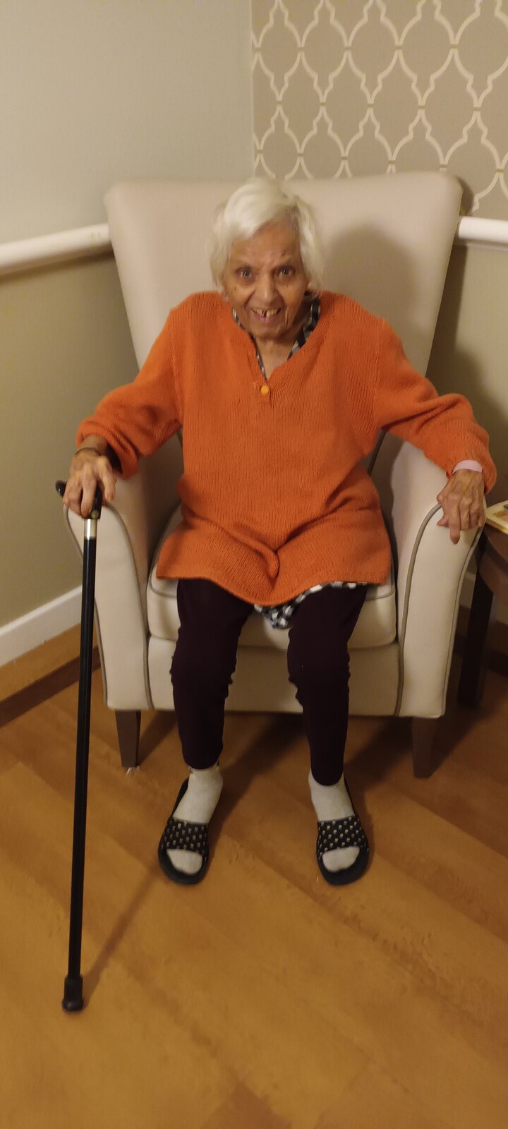 Surjit smiling warmly in an orange cardigan