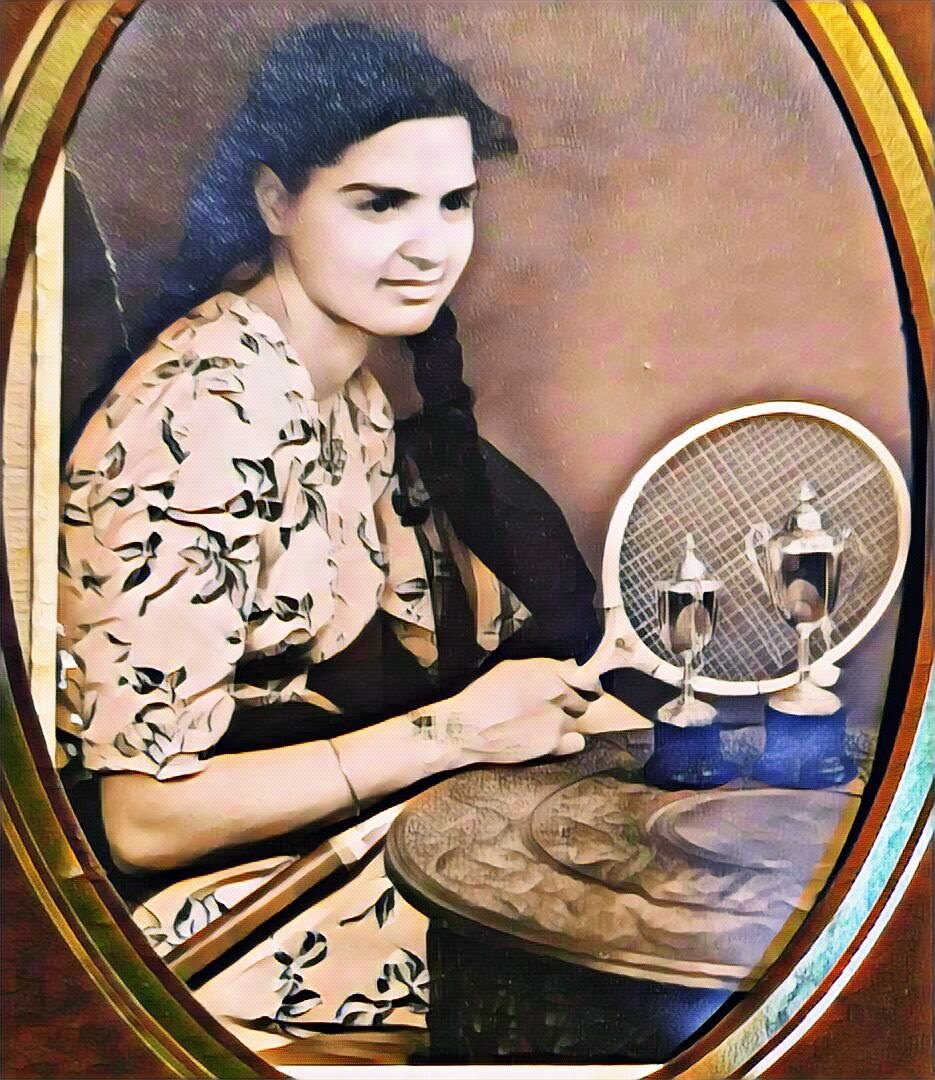 A young Surjit posing proudly with her tennis racket and trophies